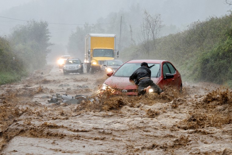 A resident helps free a stranded car as Helene strikes Boone, North Carolina