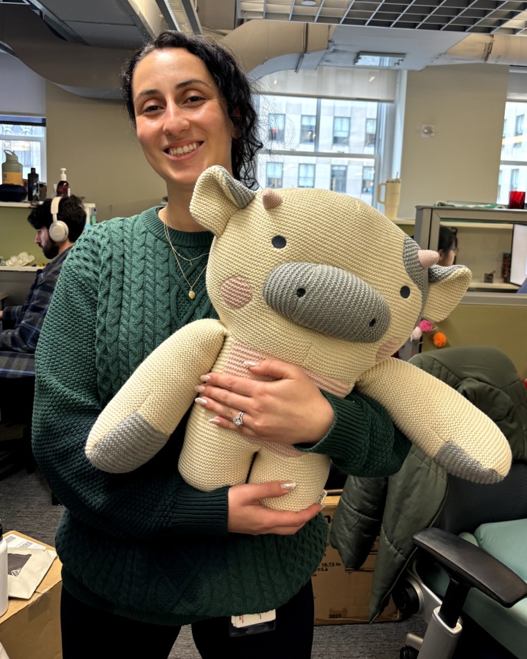 Woman holding Bearaby's Cody Cow weighted stuffed animal.