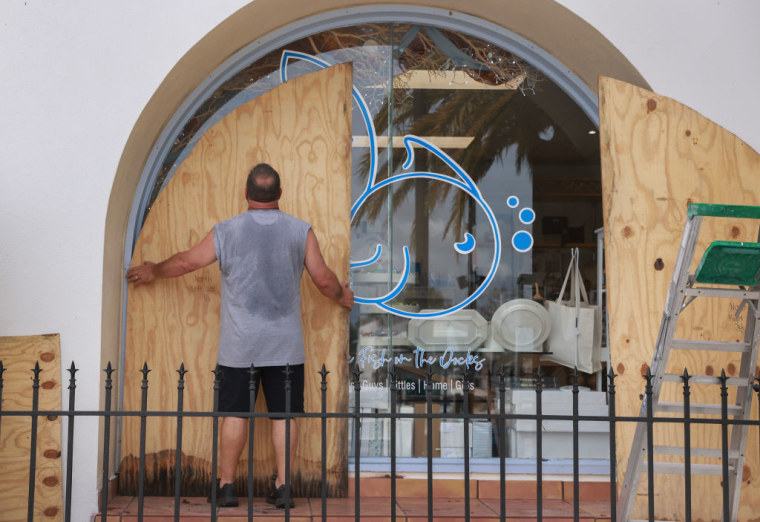 Un hombre coloca planchas de madera para proteger vidrios ante la llegada del huracán Helene,en Tarpon Springs, Florida. 