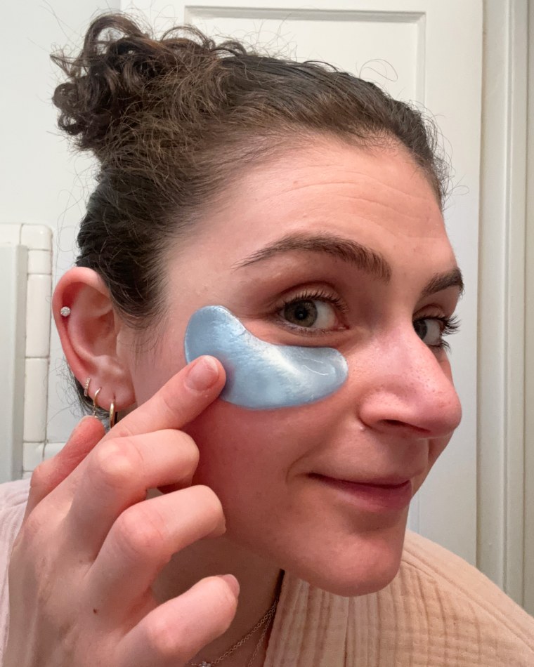 A woman applying Grace & Stella’s blue under-eye patches in a bathroom.