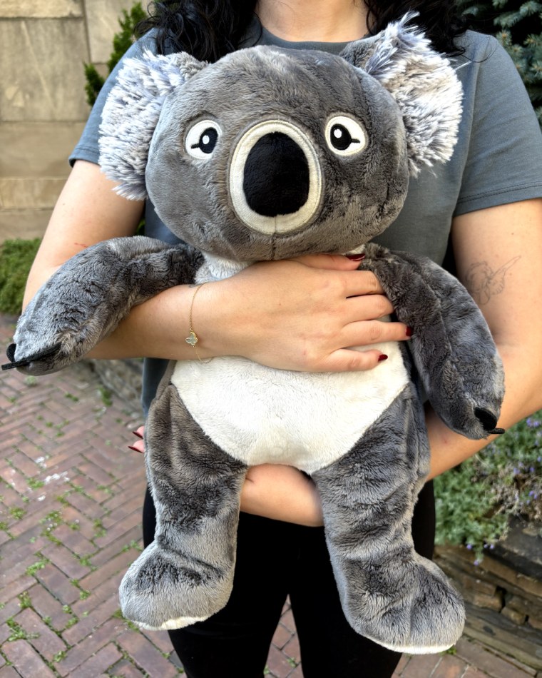 Woman hugging Hugimals' Quinn the Koala weighted stuffed animal.