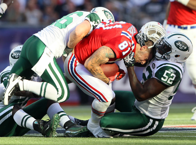 Aaron Hernandez #81 of the New England Patriots has his helmet ripped off by David Harris #52 of the New York Jets on October 9, 2011 at Gillette Stadium in Foxboro, Massachusetts.  