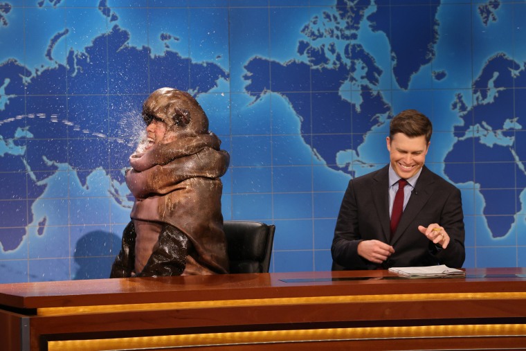 Bowen Yang as Moo Deng the hippo and Colin Jost behind him "Weekend update" Desk.