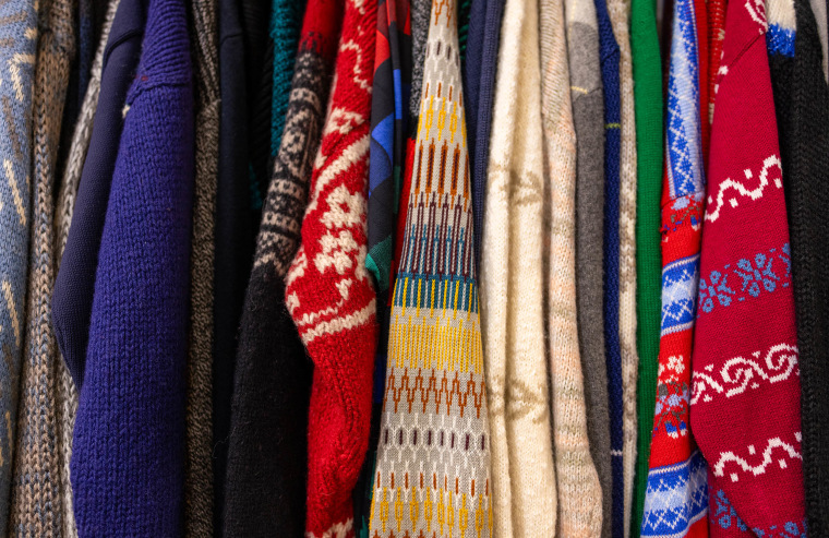 clothing rack of vintage sweaters at antique flea market