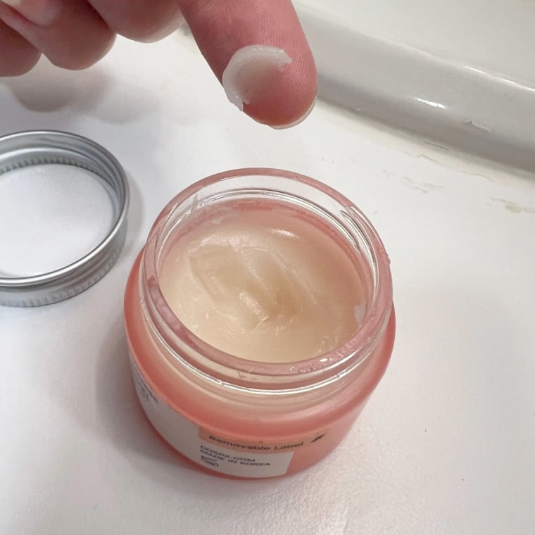 Woman scoops a tiny amount of Cosrx’s lip mask onto her finger.