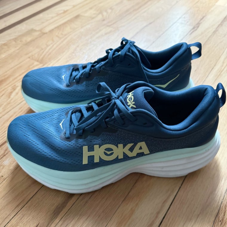 A blue pair of Hoka Bondi 8 sneakers atop a wood floor.