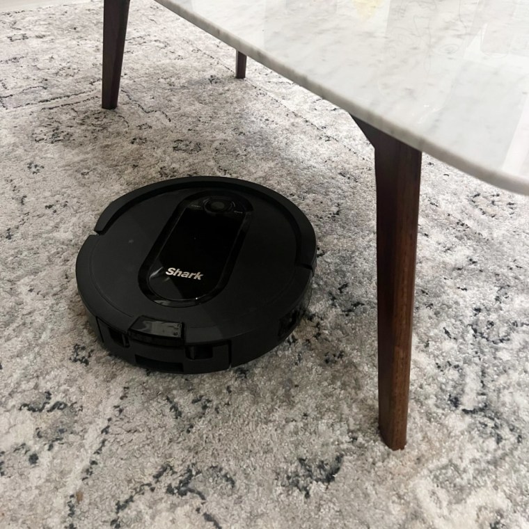 Robot vacuum on a gray carpet underneath a marble table