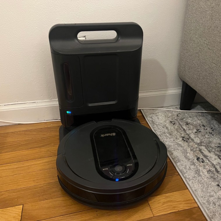 Shark robot vacuum charging on base on top of hardwood floor