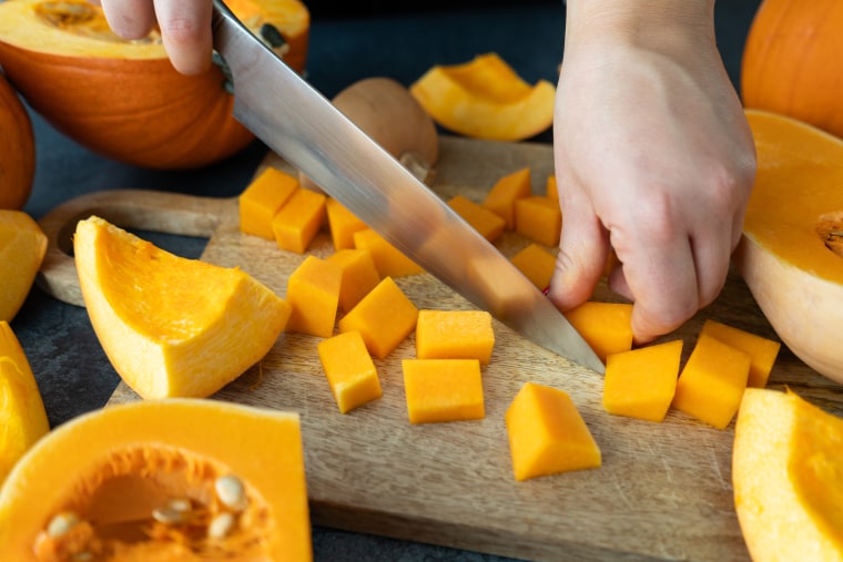 Woman dicing butternut squash pumpkin. 