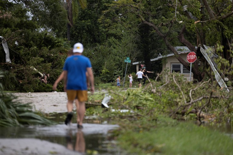 Personas caminan entre los escombros tras un tornado en Fort Myers, Florida.