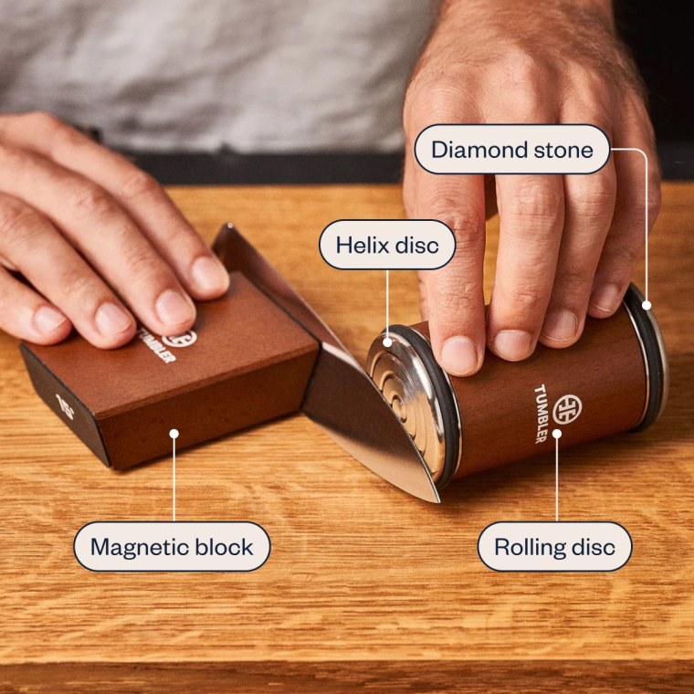 To use the Tumbler Knife Sharpener, you hold the magnetic block in place with one hand and move the rolling disc back and forth along the blade with the other.