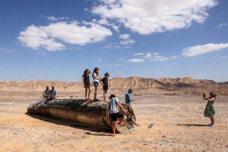 People stand on top of the remains of an Iranian missile in the Negev desert near Arad, on Oct. 2, 2024.