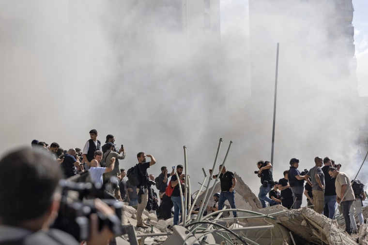 Smoke rises from a building destroyed by an Israeli airstrike as journalists and local residents visit