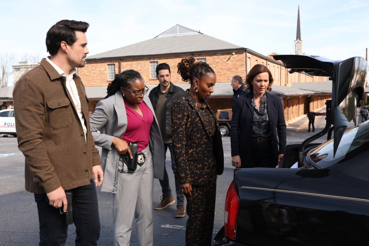 Desde la izquierda, Brett Dalton, Anisa Nyell Johnson, Karan Oberoi, Shanola Hampton y Kelli Williams parados cerca del baúl abierto de un automóvil afuera en un estacionamiento.