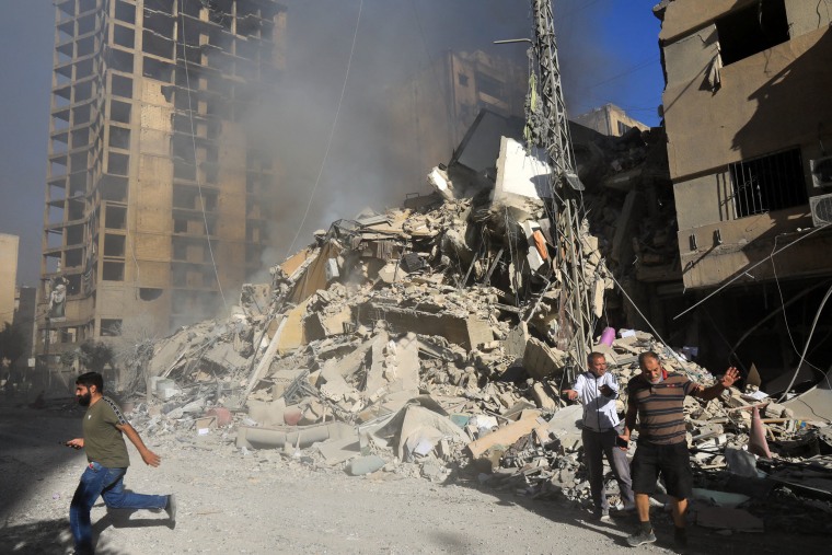 Residents walk in front of a building after it was levelled in an overnight Israeli airstrike in Moawwad in Beirut's southern suburbs on Oct. 3, 2024.