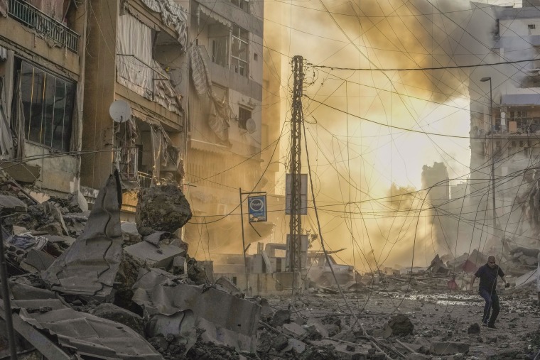 A man runs for cover following an Israeli airstrike in Dahiyeh, Beirut.