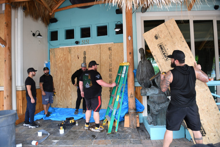 Employees of The Beach Club board up the front of the club on on Siesta Key in Sarasota, Fla., on Oct. 7, 2024.