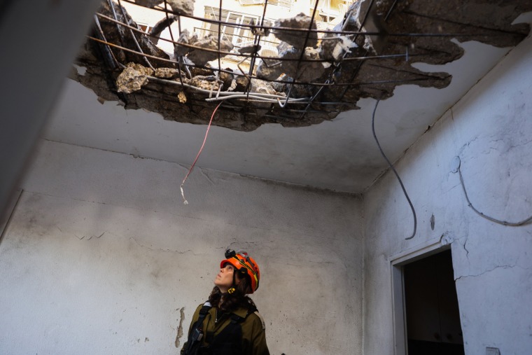 A member of Israeli emergency services inspects a damaged building which was hit with a rocket launched from Lebanon