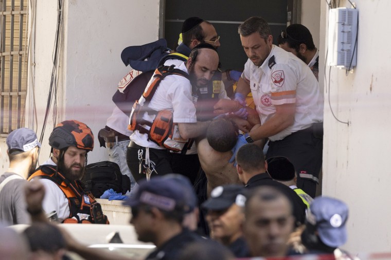 Emergency workers carry an injured man, the suspect in a stabbing attack