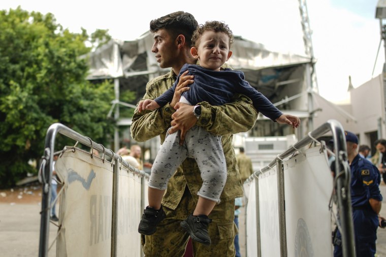 A Turkish soldier carries a child on board of a Turkish military ship as  hundreds of people, mostly Turkish citizens, are evacuated from Lebanon to Turkey, in Beirut's port Oct. 10, 2024. 