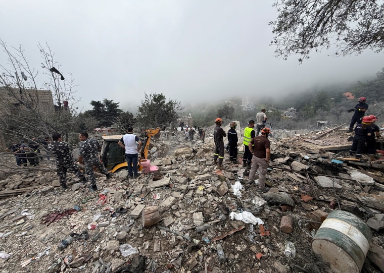 Civil Defense members work at a site damaged by an Israeli air strike in Aitou