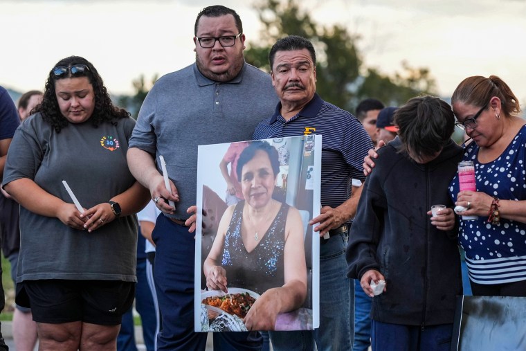 The family of Bertha Mendoza carries her portrait at a candlelight vigil