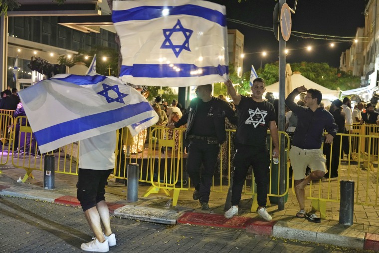 People wave the Israeli flag as they celebrate the news of the death of Hamas leader Yahya Sinwar, in Netanya, Israel