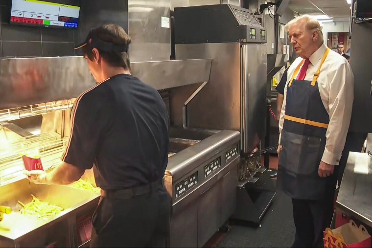 Donald Trump stands in a McDonald's kitchen wearing an apron