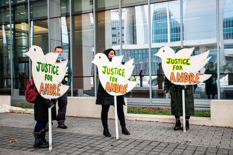 People hold signs in the shape of white doves that say "Justice for Andre"