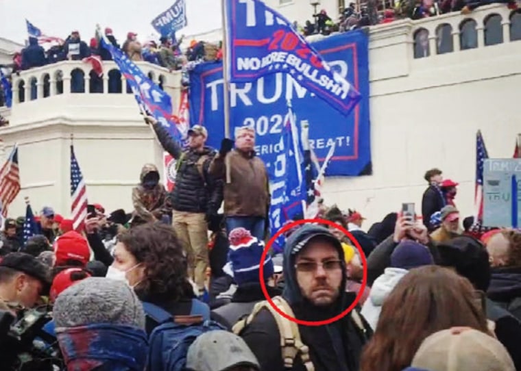 Jonathan Newcomb at the Capitol on January 6, 2021, with a banner in the background he brought.