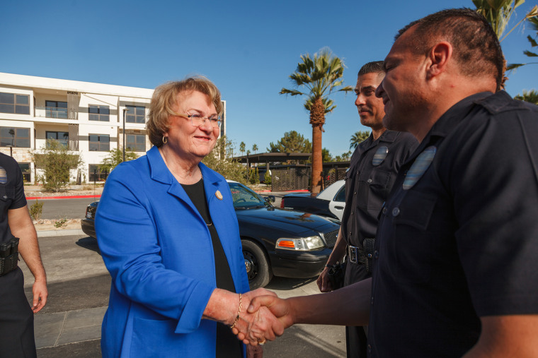 Foto de la sujeto Lisa Middleton con un traje azul estrechando la mano de un oficial de policía. 