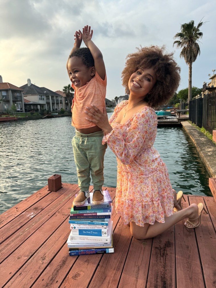 Lauren Eaton Spencer and her son pose for a photo outside near a pool, the son stands on a stack of books