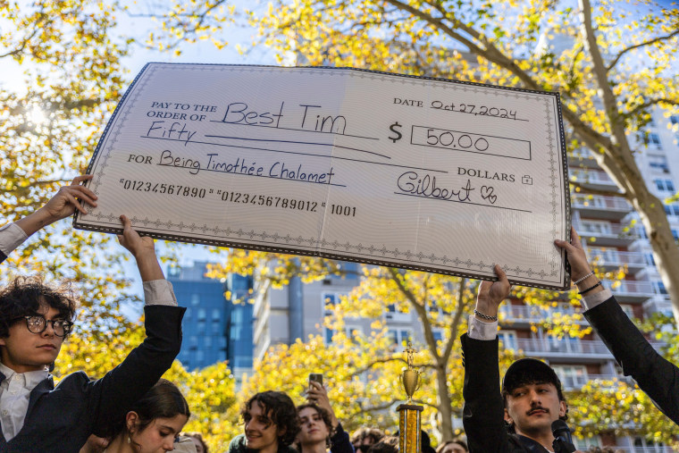 A giant check for fifty dollars is held by people