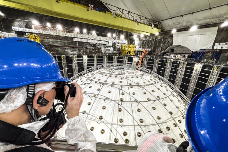 Periodistas posan encima de un globo en el Observatorio Subterráneo de Neutrinos en Jiangmen, provincia china de Guangdong, el 11 de octubre.