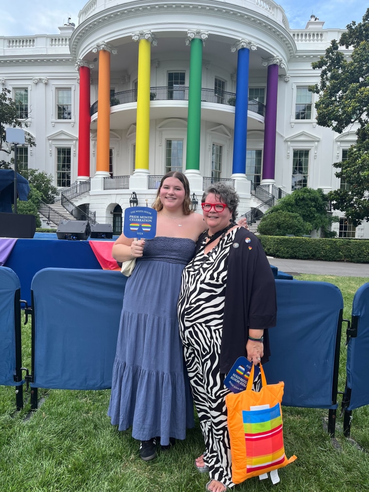 Young woman and older woman standing outside of the White House, the younger woman holds a sign that reads "Pride Month Celebration" 