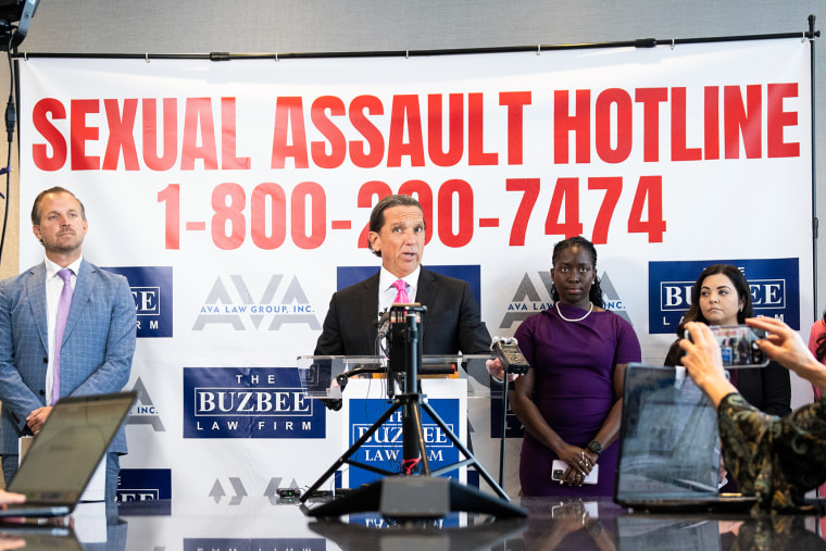 Tony Buzbee speaks in front of a banner that reads "Sexual Assualt Hotline 1-800-200-7474"