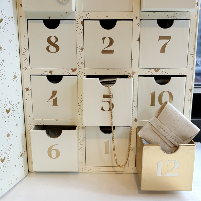 Abbott Lyon’s Advent calendar standing up in front of a window with a few drawers pulled out to reveal necklaces and bracelets inside.