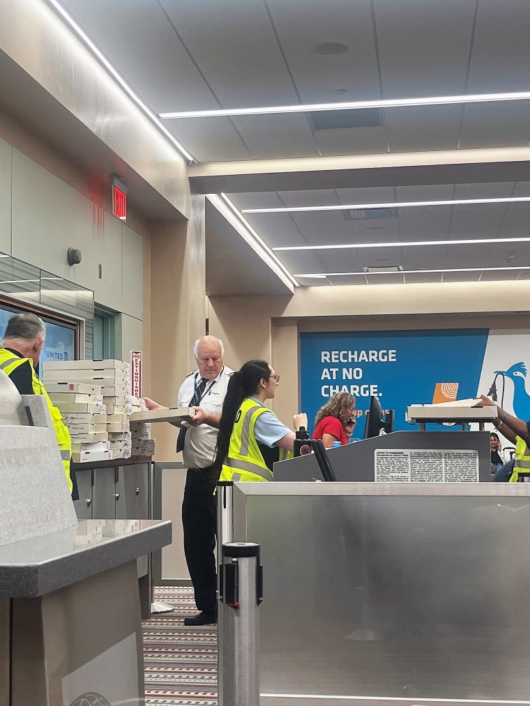 United Airlines pilot passing out free pizza to passengers.