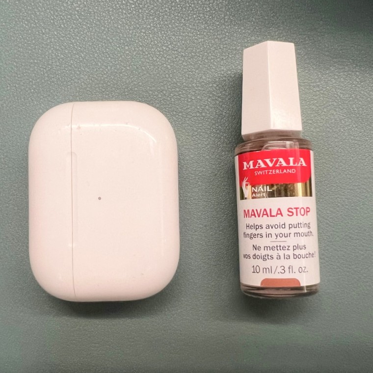 Mavala No-Bite Polish sobre un fondo verde junto al estuche de los AirPods Pro.