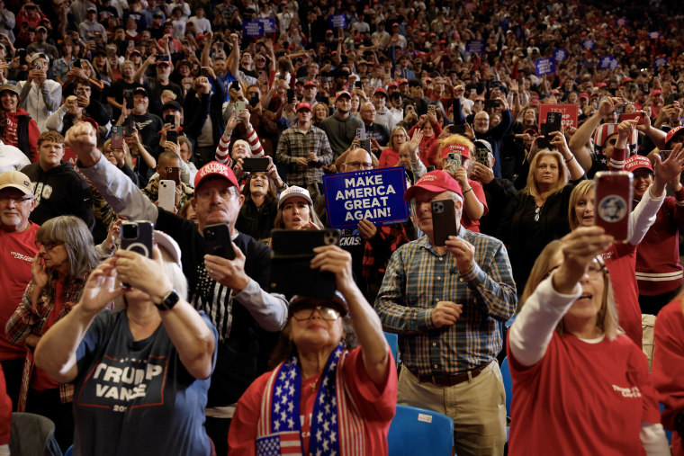 Trump supporters hold placards and phones.