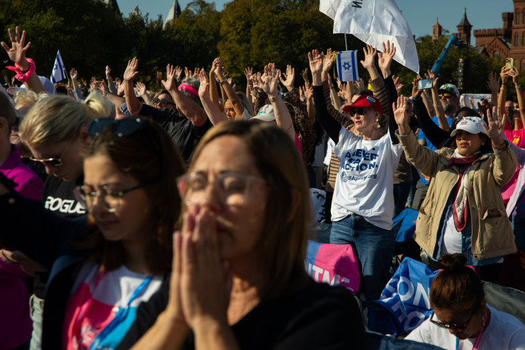 A large crowd raises their hands outside