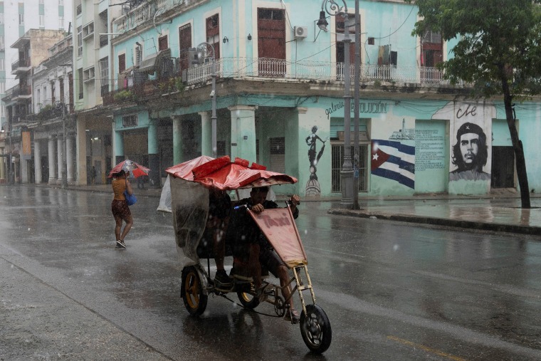 People pass by on the street as Hurricane Rafael passes by Havana, Cuba, on Wednesday.