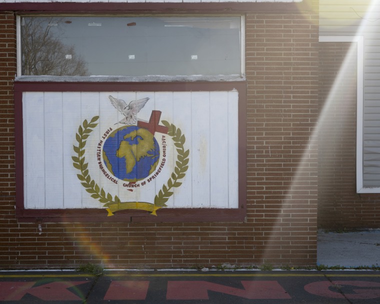 The PEEHSO Church - Première Eglise Evangélique Haitienne de Springfield, OH, displays a hand-painted sign of a dove, a cross and a globe. 