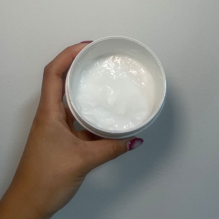 Woman holds open Crown Affair’s The Renewal Hair Mask.