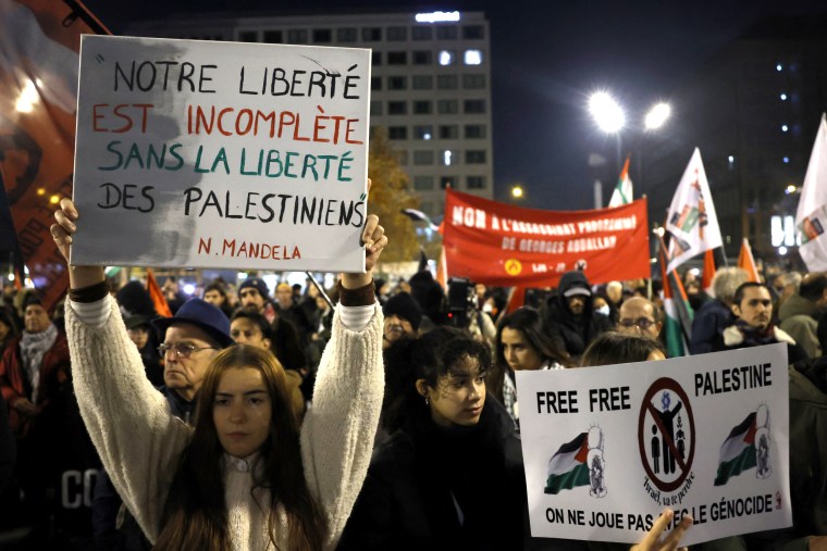 Protestors hold signs during a demonstration against the soccer match between France and Israel in Aubervilliers, France