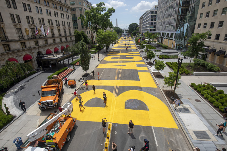 People walk down 16th street after volunteers, with permission from the city, painted "Black Lives Matter" on the street near the White House 