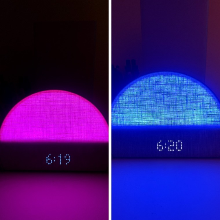Hatch Restore 2 on a table in the dark, lit up pink with the time 6:19 on the display.
Right - Hatch Restore 2 on a table in the dark, lit up blue with the time 6:20 on the display.