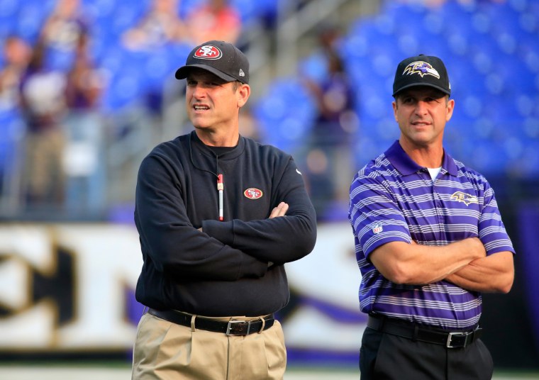 Head coach Jim Harbaugh of the San Francisco 49ers and his brother head coach John Harbaugh of the Baltimore Ravens talk before the start of their NFL pre-season game at M&T Bank Stadium on August 7, 2014 in Baltimore, Maryland.  