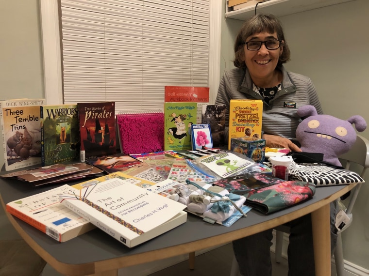 Liz Sinclair, seated to the right of a table covered in various books and other items.