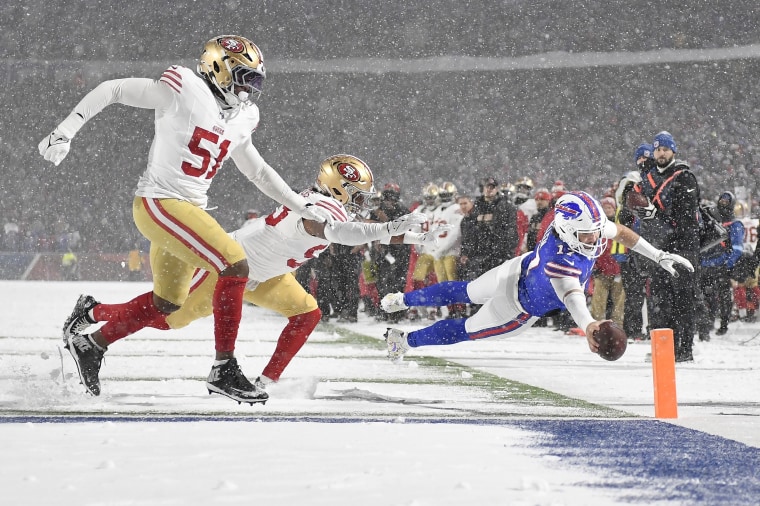 O quarterback do Buffalo Bills, Josh Allen, corre em direção à end zone para ultrapassar o lado defensivo do San Francisco 49ers, Robert Beal Jr., e o linebacker Dee Winters.